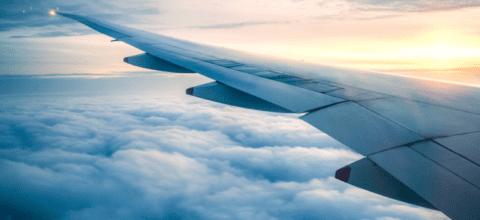 A closeup of an airplane wing above the clouds.